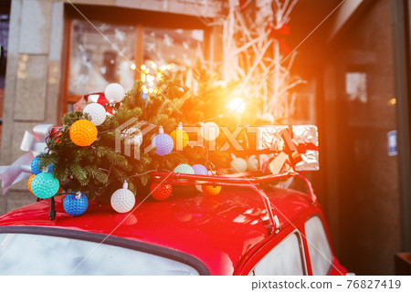 Red retro car with a Christmas tree fir tied to the roof. Red retro car with a Christmas tree fir tied to the roof. 76827419