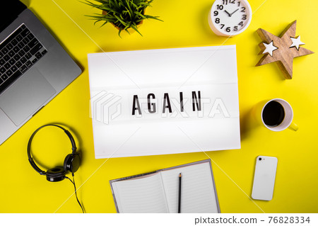 Lightbox with text message AGAIN on yellow office student workspace background Lightbox with text message AGAIN on yellow office student workspace background 76828334