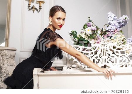young pretty lady in black lace fashion style dress posing in rich interior of royal hotel room, luxury lifestyle people concept 76829125