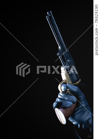 humans hand in black glove with revolver 76829190