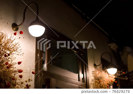 wall sconce lamp at the backyard near door exterior lighting with decorative dried flowers closeup night scene nobody. wall sconce lamp at the backyard near door exterior lighting with decorative dried flowers closeup night scene nobody. 76829278