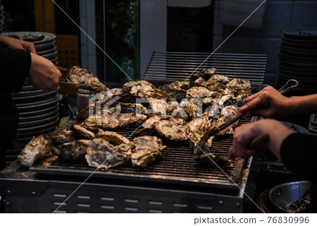 A place where multiple oysters are baked in a shopping district 76830996