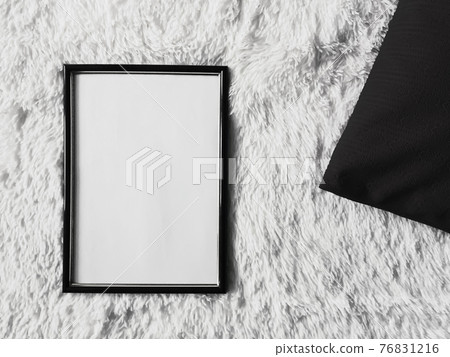 Thin wooden frame with blank copyspace as poster photo print mockup, black cushion pillow and fluffy white blanket, flat lay background and art product Thin wooden frame with blank copyspace as poster photo print mockup, black cushion pillow and fluffy white blanket, flat lay background and art product 76831216