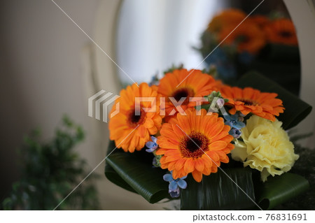 A bouquet of orange gerberas placed in front of the mirror 76831691