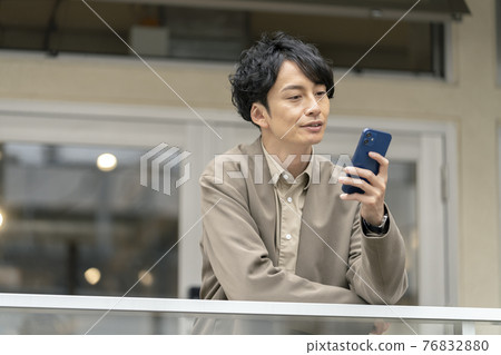 A man in his thirties looking at the screen of a smartphone A man in his thirties looking at the screen of a smartphone 76832880