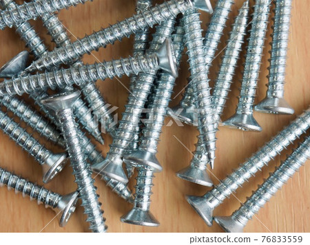 Silver screws and wooden board background Silver screws and wooden board background 76833559