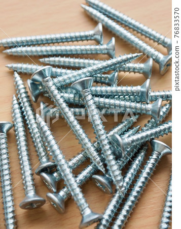 Silver screws and wooden board background Silver screws and wooden board background 76833570