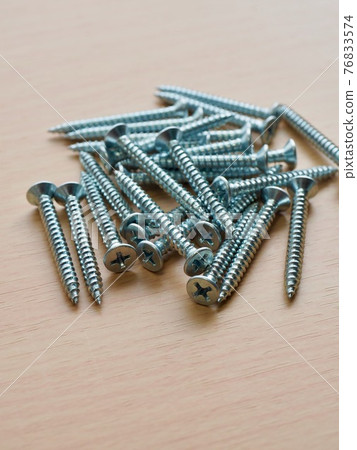 Silver screws and wooden board background 76833574