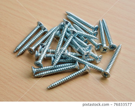 Silver screws and wooden board background Silver screws and wooden board background 76833577