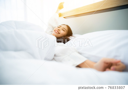 Beautiful women asian wake up in morning in bedroom. She is stretching and feeling fresh 76833807