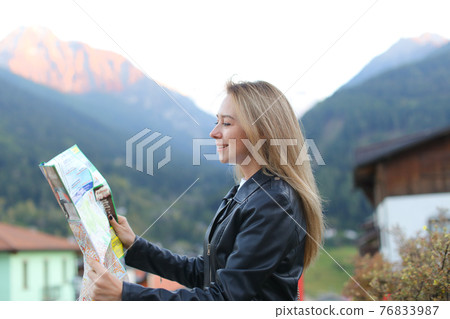 Blonde woman looking at map in mountain village. Blonde woman looking at map in mountain village. 76833987