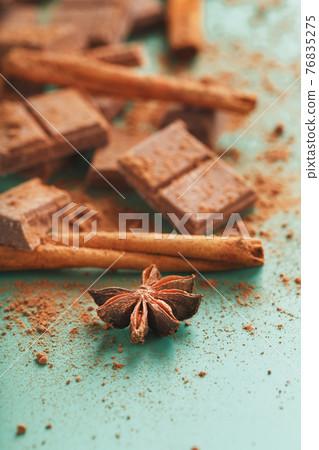 Chocolate broken into slices with cocoa powder and spices on a green background Chocolate broken into slices with cocoa powder and spices on a green background 76835275