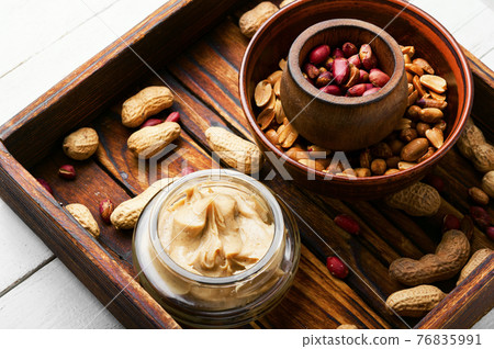 Homemade peanut butter and heap of nuts 76835991