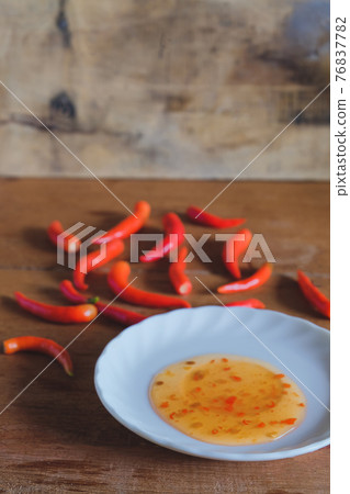 Red chili peppers and chili sauce in dish on wood table Red chili peppers and chili sauce in dish on wood table 76837782