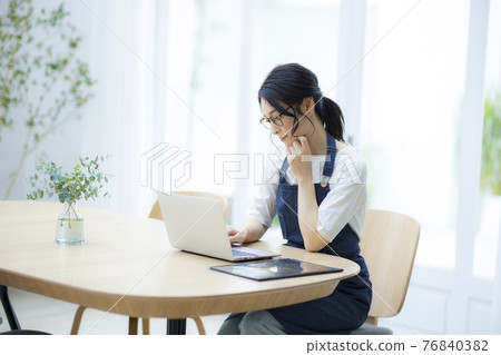Woman in an apron looking at a computer 76840382