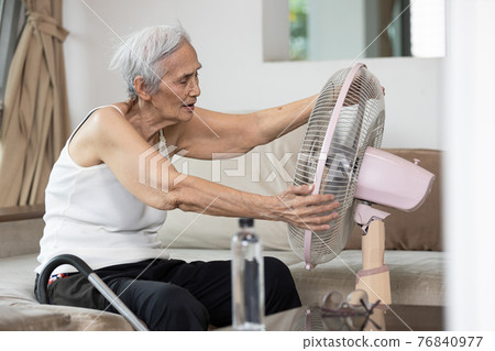 Overheated asian senior woman sweating,high temperature in sunny day while stay at home,cooling herself in front of an electric fan,old elderly suffering from heat,hot summer weather,lifestyle concept Overheated asian senior woman sweating,high temperature in sunny day while stay at home,cooling herself in front of an electric fan,old elderly suffering from heat,hot summer weather,lifestyle concept 76840977