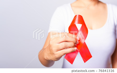 Closeup of female with red ribbon HIV AIDS on hand Closeup of female with red ribbon HIV AIDS on hand 76841316