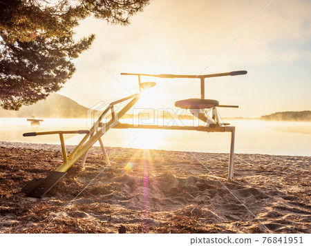 Colorful sunset with seesaw on beach. Teeter totter with wooden chairs Colorful sunset with seesaw on beach. Teeter totter with wooden chairs 76841951