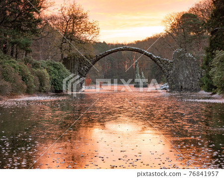 Chill autumn morning in park Kromlau. Round Arch basalt bridge Chill autumn morning in park Kromlau. Round Arch basalt bridge 76841957