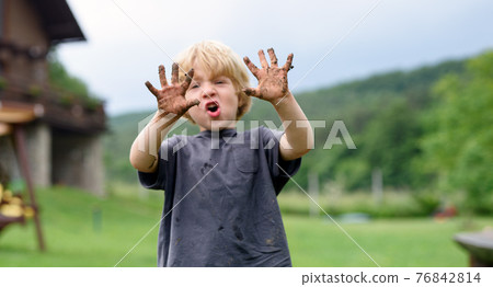 Small boy with dirty hands standing in vegetable garden, sustainable lifestyle. Small boy with dirty hands standing in vegetable garden, sustainable lifestyle. 76842814
