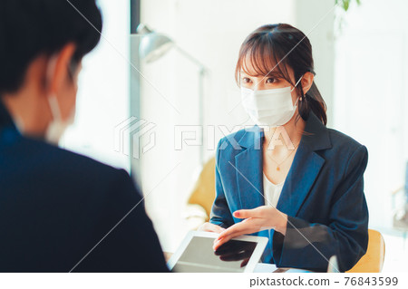A woman in a mask serving customers through an acrylic board A woman in a mask serving customers through an acrylic board 76843599