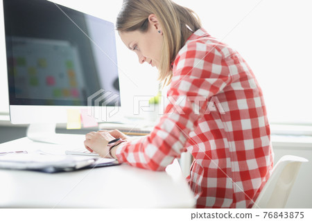 Hunched woman typing on computer keyboard at table 76843875