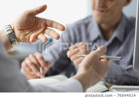 Men are discussing at table in office and gesturing closeup 76844014