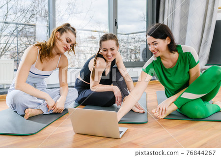 Girls in sportswear look at laptop screen 76844267