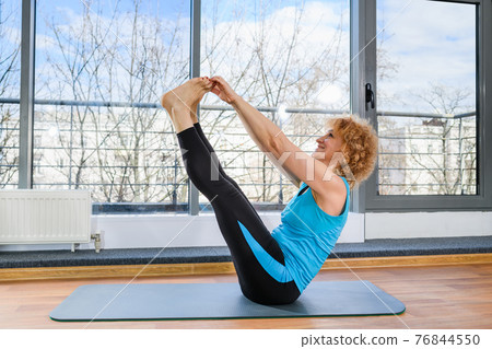 Mature fit woman warming up body indoors Mature fit woman warming up body indoors 76844550