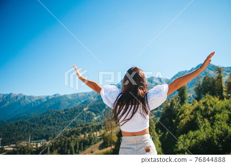 Beautiful happy young woman in mountains in the background of fog Beautiful happy young woman in mountains in the background of fog 76844888