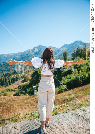 Beautiful happy young woman in mountains in the background of fog 76844889