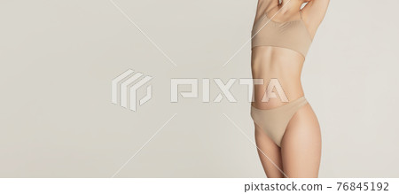Cropped slim tanned beautiful woman in underwear isolated over light background. Cropped slim tanned beautiful woman in underwear isolated over light background. 76845192