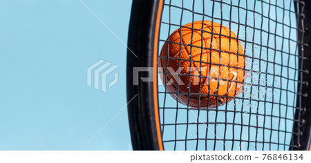 A hit with a tennis racket to a wet ball, on a background of blue sky, close up view A hit with a tennis racket to a wet ball, on a background of blue sky, close up view 76846134