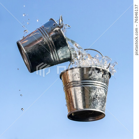 A pouring water from falling bucket to bucket, on a background of blue sky. 76846137