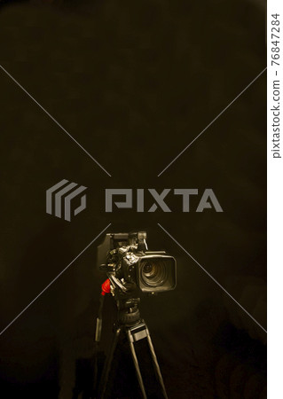 Digital camera and tripod against black background Digital camera and tripod against black background 76847284