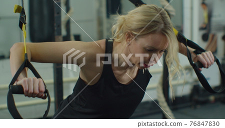 Female athlete training with trx strap hanging body for training with body resistance system in fitness gym. Concept of process pump up body and keeping fit. Female athlete training with trx strap hanging body for training with body resistance system in fitness gym. Concept of process pump up body and keeping fit. 76847830
