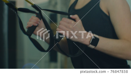 Closeup fit woman trains with trx resistance system in a modern gym. Healthy lifestyle. 76847838