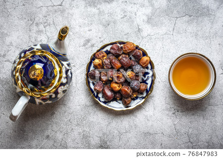 Popular food during Iftar - dry dates, teapot, bowl with black tea on concrete background Top view Flat lay Muslim holiday of holy month of Ramadan Popular food during Iftar - dry dates, teapot, bowl with black tea on concrete background Top view Flat lay Muslim holiday of holy month of Ramadan 76847983