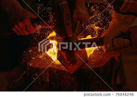 Blacksmiths hit molten metal with hammers close up Blacksmiths hit molten metal with hammers close up 76848246
