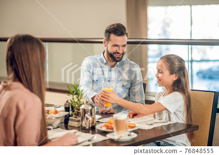 Kids and their dad sitting at the table in the restaurant 76848555
