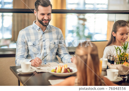 Kids and their dad sitting at the table in the restaurant Kids and their dad sitting at the table in the restaurant 76848556