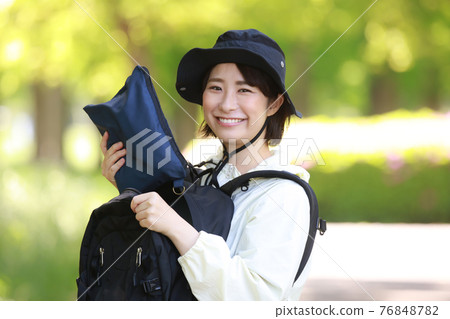 一個女人從背包裡拿出雨具 一個女人從背包裡拿出雨具 76848782