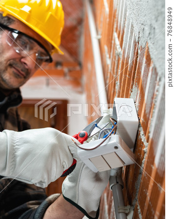 Electrician at work in an electrical system of a construction site. Construction industry. Electrician at work in an electrical system of a construction site. Construction industry. 76848949