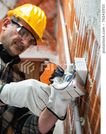 Electrician at work in an electrical system of a construction site. Construction industry. Electrician at work in an electrical system of a construction site. Construction industry. 76848950