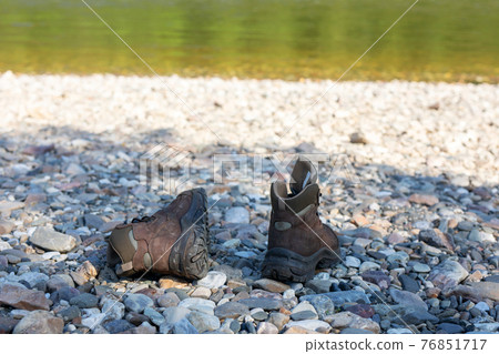 The choice of shoes for tourism and trekking. Brown boots stand on a stony bank. 76851717