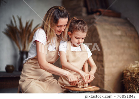 mother and daughter mold with clay, enjoying pottery art and pro 76851842