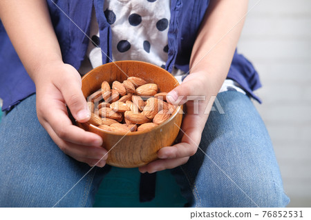close up child girl hand holding a bowl on almond close up child girl hand holding a bowl on almond 76852531