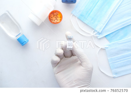 hand in latex gloves holding glass ampoule vaccine, with copy space hand in latex gloves holding glass ampoule vaccine, with copy space 76852570