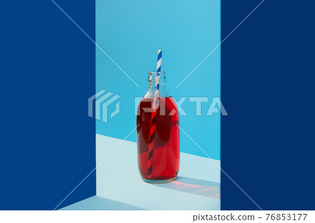 Refreshing cranberrie lemonade cocktail in bottle with palm leaf on blue creative background Refreshing cranberrie lemonade cocktail in bottle with palm leaf on blue creative background 76853177