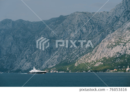 Luxurious white motor yacht sails along the Kotor bay with mountains in the background 76853816